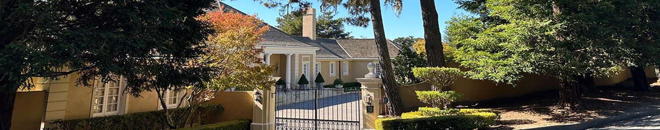 Elegant yellow house with a gated entrance and manicured shrubs.