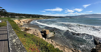 Coastal view with rocky shore and waves under a clear blue sky.