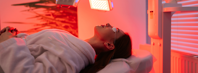 Woman relaxing with LED light therapy on her face in a spa.